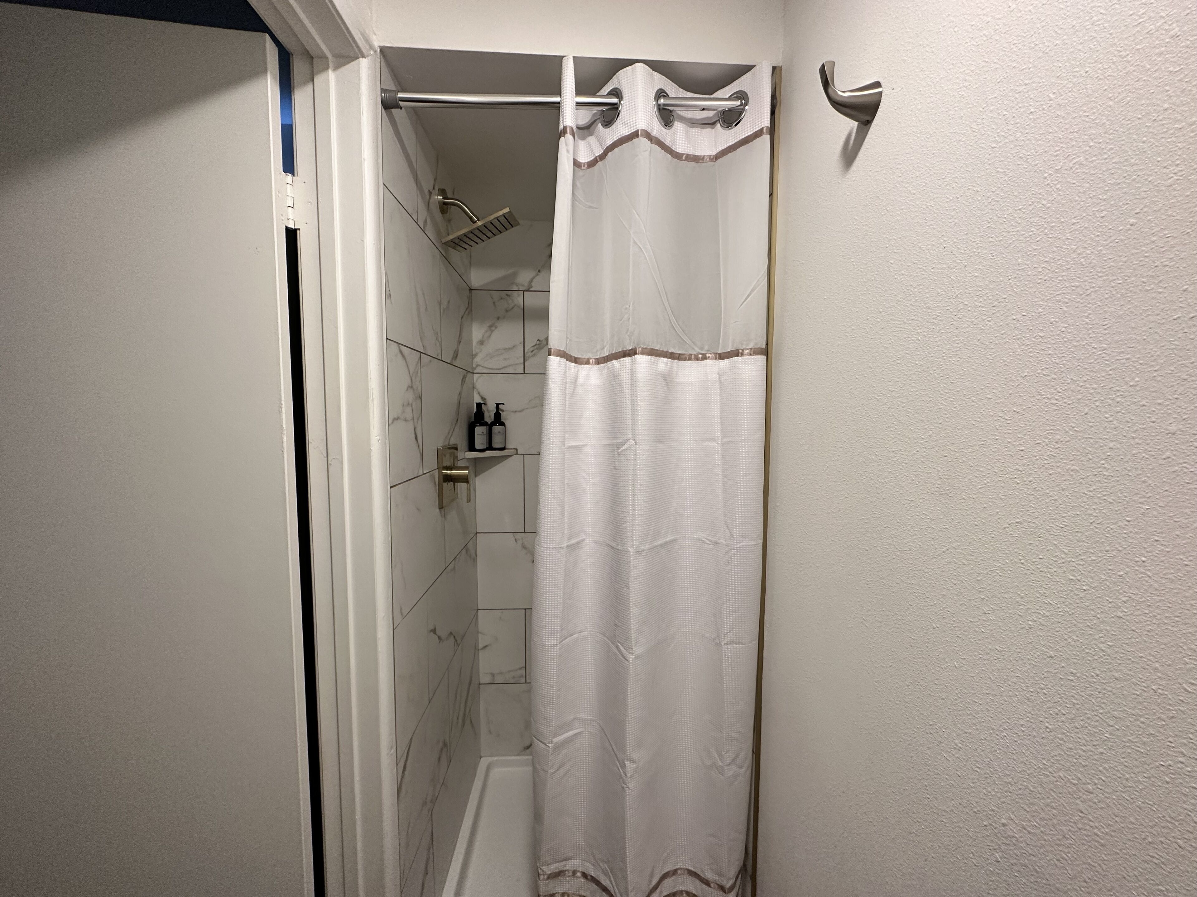 Ein Badezimmer mit Dusche, Handtuchhalter und Ablage für Toilettenartikel.