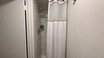 Ein Badezimmer mit Dusche, Handtuchhalter und Ablage für Toilettenartikel.