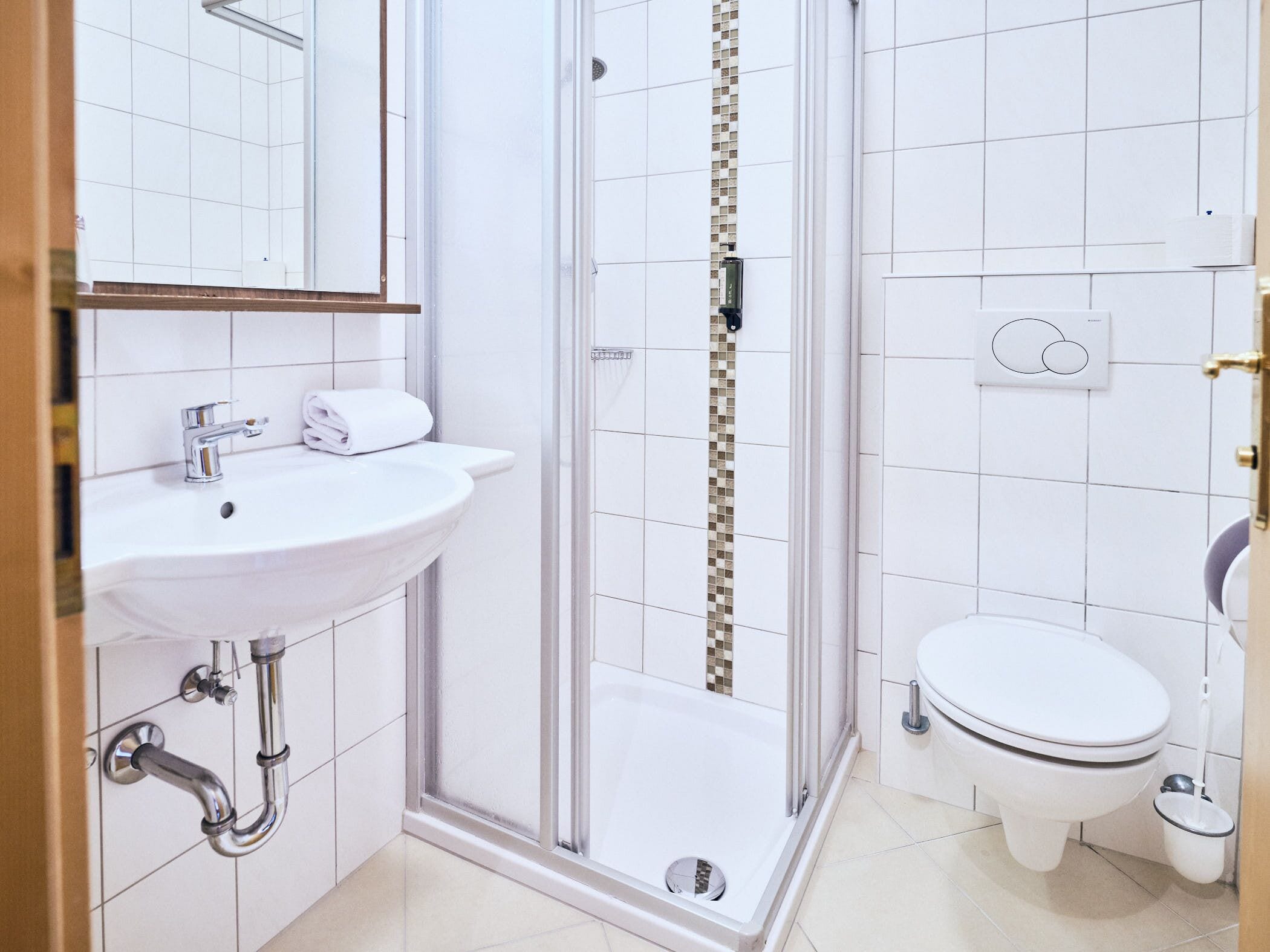 Une salle de bain moderne avec un lavabo blanc, une douche à parois de verre et des toilettes.