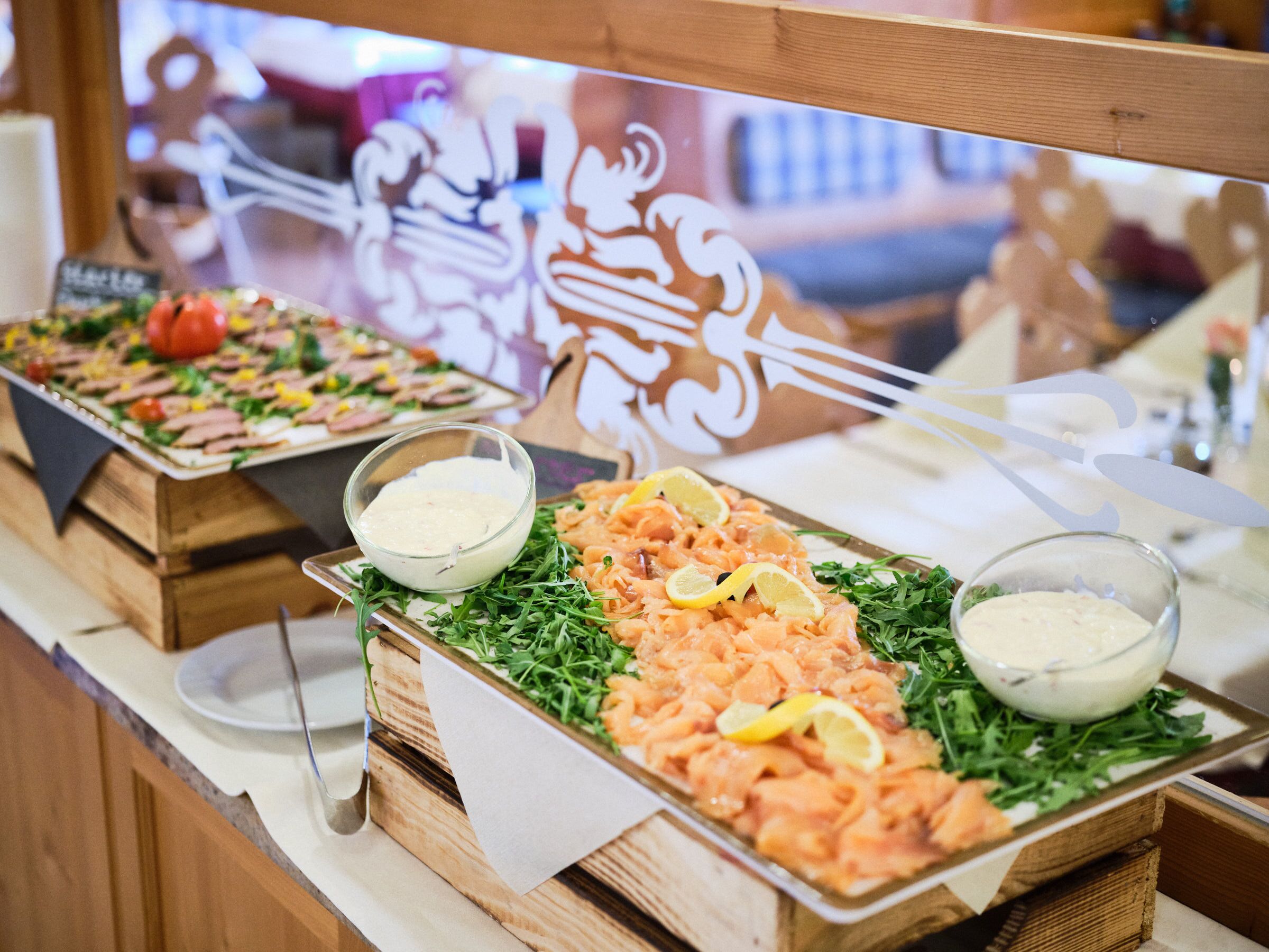 Een buffet met diverse gerechten, waaronder zalm en salade, en twee dressingschalen.