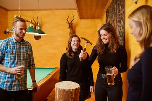 A group of people in a room with a pool table, wooden walls, and a painting. - Hotel Kirchboden by Alpeffect Hotels (Wagrain)