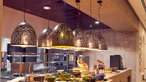 Een buffetgedeelte met een lange toonbank, diverse gerechten en hangende吊り灯
