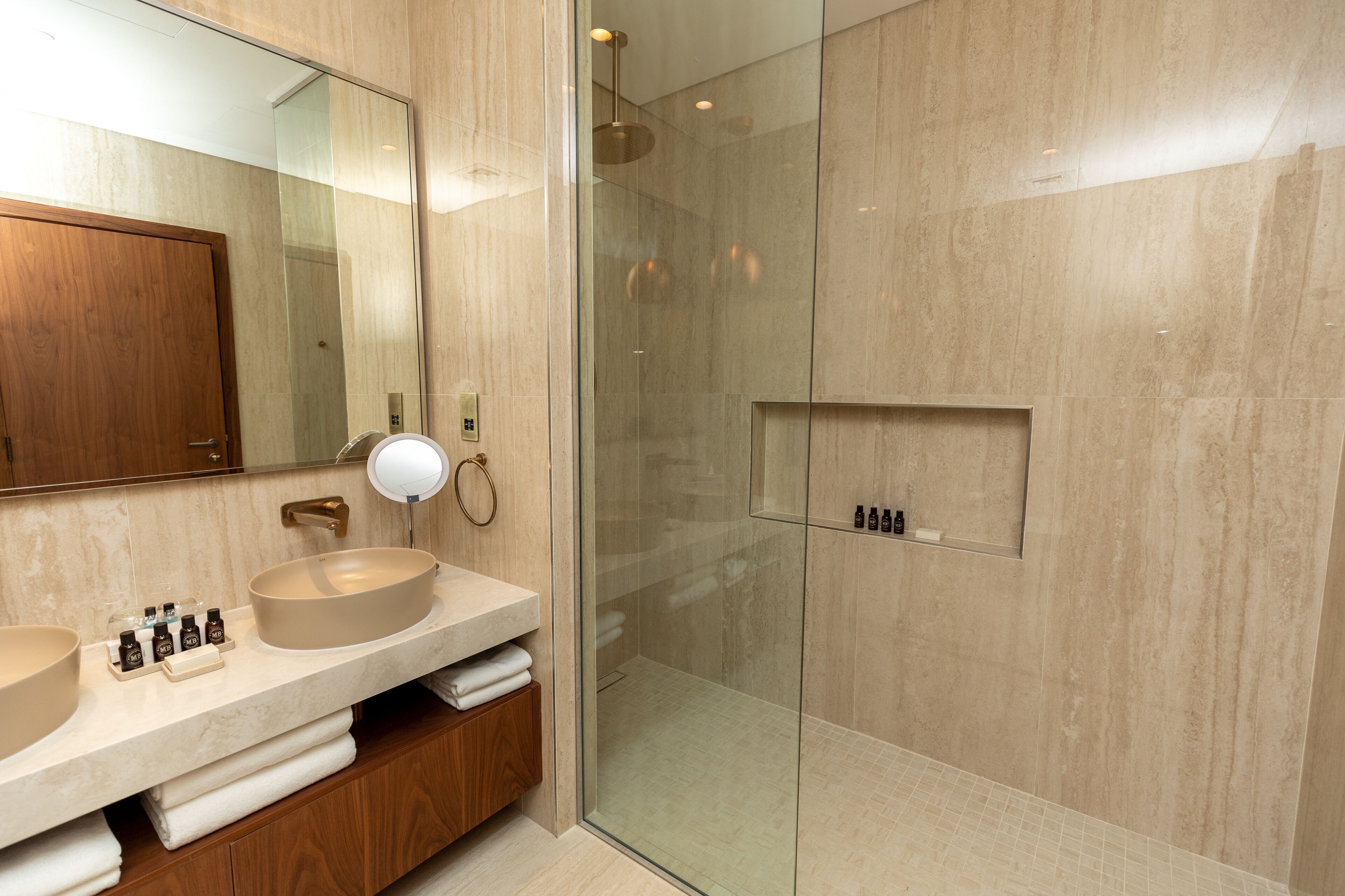 A modern bathroom with two sinks, a glass-enclosed shower, and a wooden vanity.