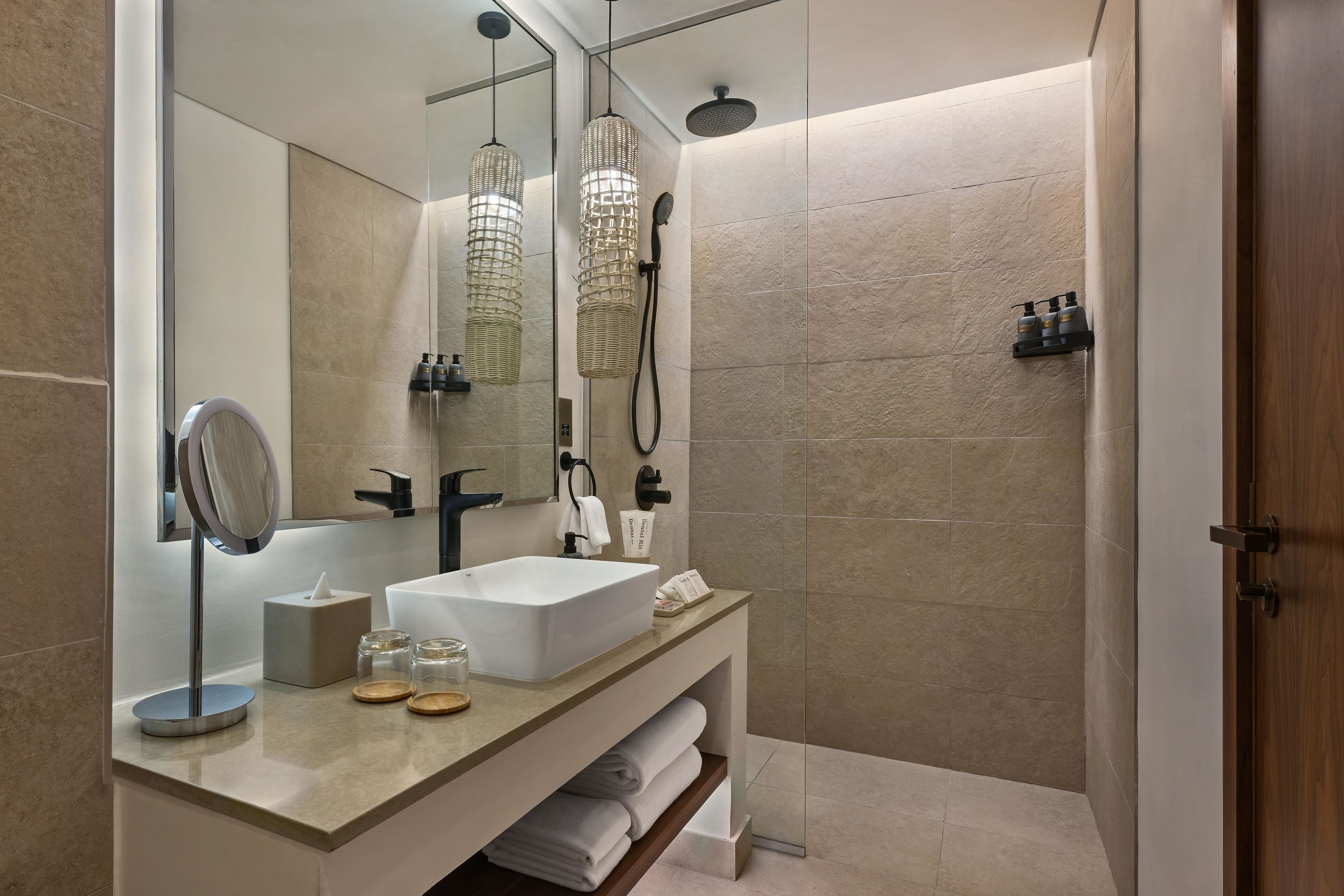 A modern bathroom with a large mirror, a white sink, and a shower area.