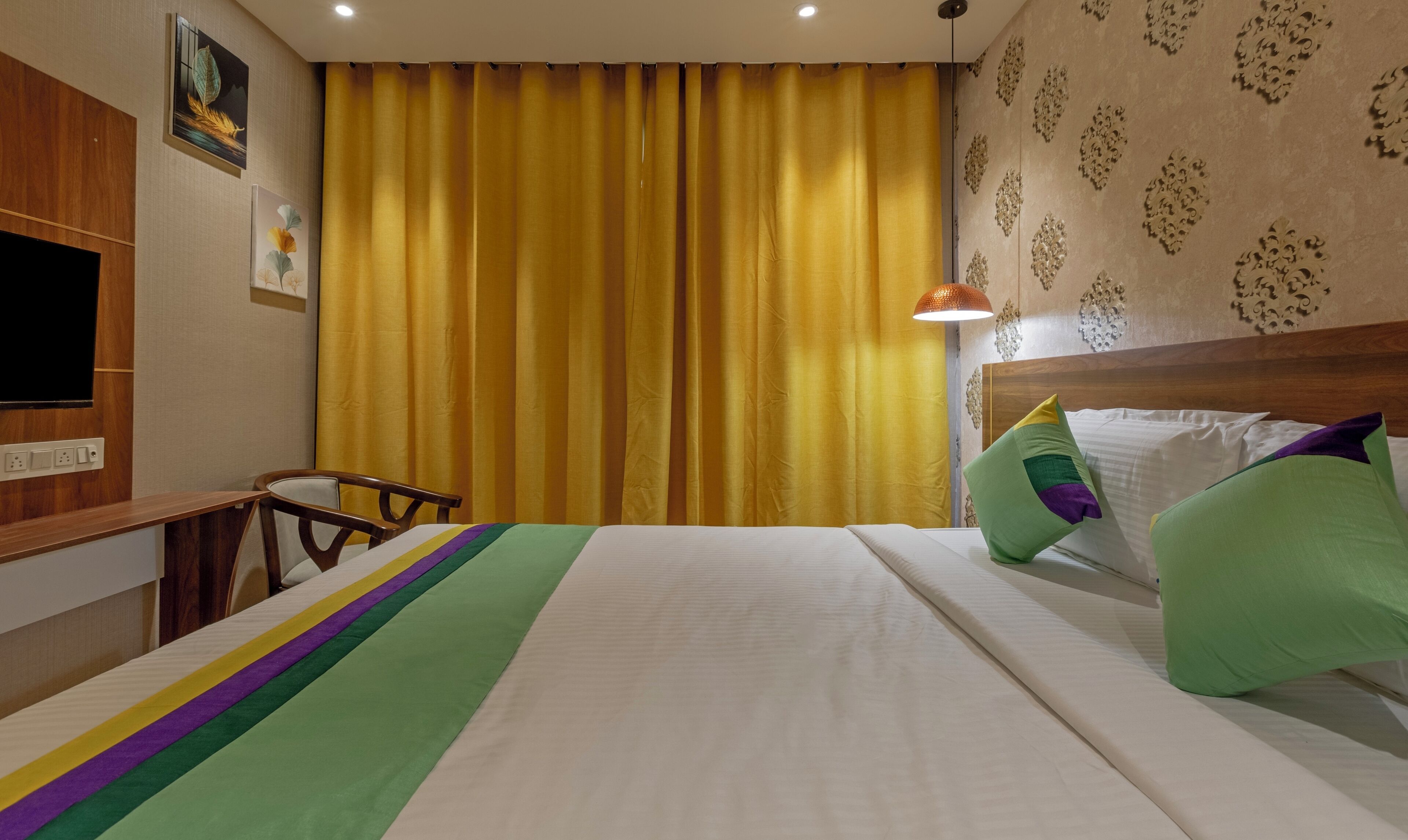 Una habitación de hotel con una cama, un escritorio, una silla y un televisor.