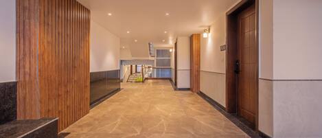 Un pasillo moderno con piso de mármol, paneles de madera en un lado y una puerta con el número.