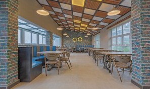 A modern cafe with brick walls, wooden ceiling panels, and large windows. - Treebo Windsor Heights (Ootacamund)