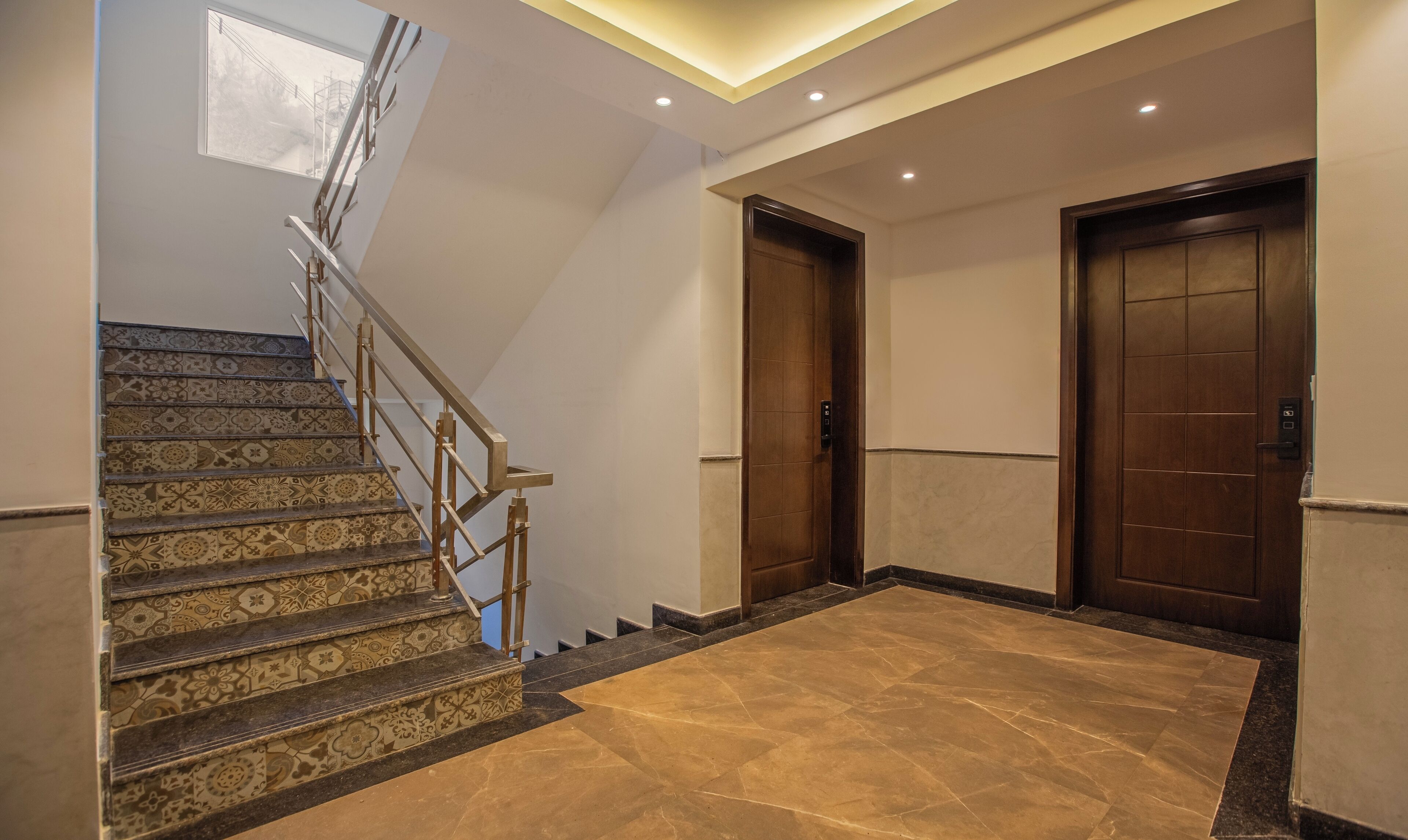 A staircase with patterned tiles and a handrail, leading to a door with a keypad lock.