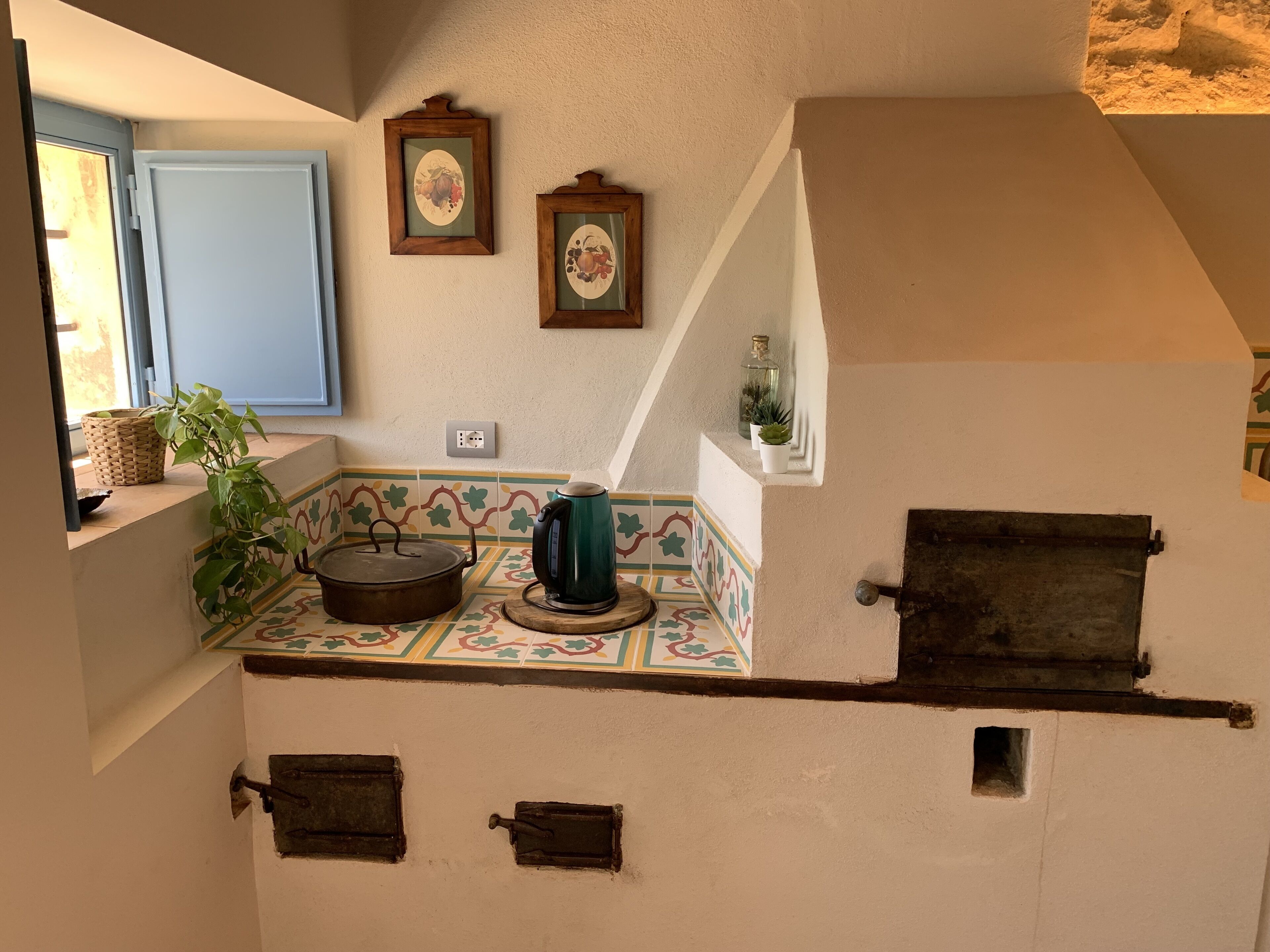 Una cocina con salpicadero de azulejos, estufa, hervidor y ventana con vistas.