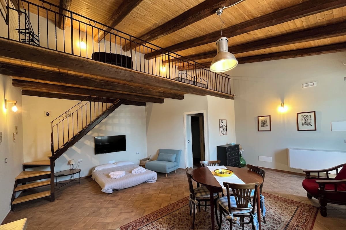 A spacious living area with a wooden staircase, a dining table with chairs, and a cozy seating area.