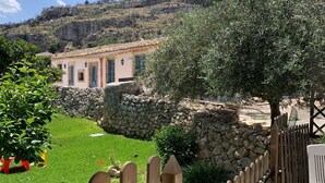 A stone wall, a wooden fence, and a building with a tiled roof. - Masseria Santacatrini (Melilli)