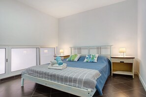 Quarto com cama, duas mesas de cabeceira, janela e armário.