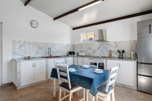 Una cocina con armarios blancos, un mantel azul y un reloj en la pared.