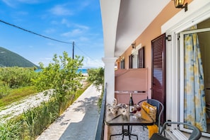 A balcony with a table, chair, and a bottle of wine.