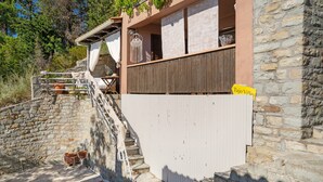 Ein Steinhaus mit einer hölzernen Treppe, die zu einem Balkon führt.