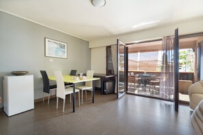 A dining area with a table, chairs, a refrigerator, and a sliding glass door leading to an outdoor patio.