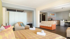 Ein Hotelzimmer mit Bett, Sofa, Essbereich und einer Küchenzeile.