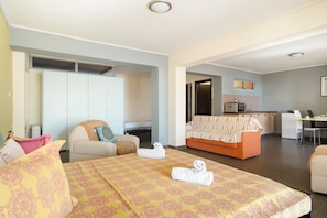 Une chambre d’hôtel comprenant un lit, un canapé, un coin repas et une kitchenette.