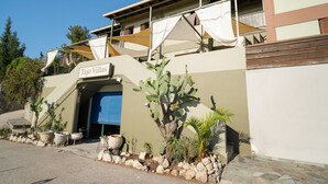 Ein Gebäude mit einem Schild, auf dem 'Tajo Villas' steht, einer Kaktee und Topfpflanzen entlang des Eingangsbereichs.