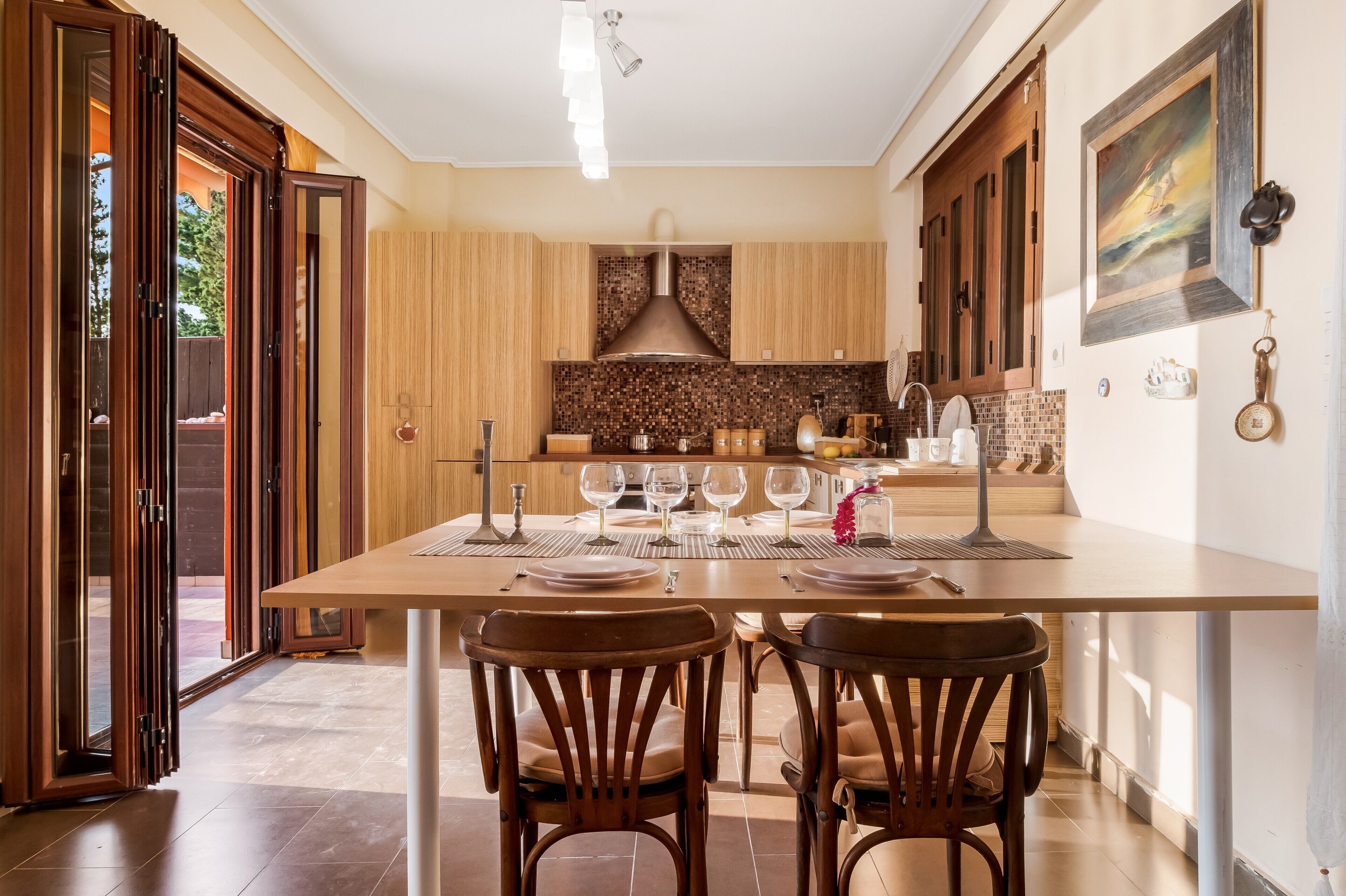 A modern kitchen with a dining table set for four, wooden cabinets, and a large window.
