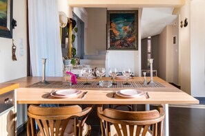 Un coin repas avec une table en bois, dressée pour quatre personnes, entourée de chaises en bois.