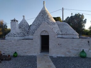 A small, white, stone-roofed building with a central doorway and two smaller structures on either side. - Villa "Trullo Libellula" with Private Garden, Private Pool, and Wi-Fi (Ceglie Messapica)