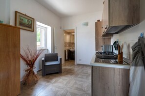 A compact kitchen with a dining area, a window, and a view of a bathroom.