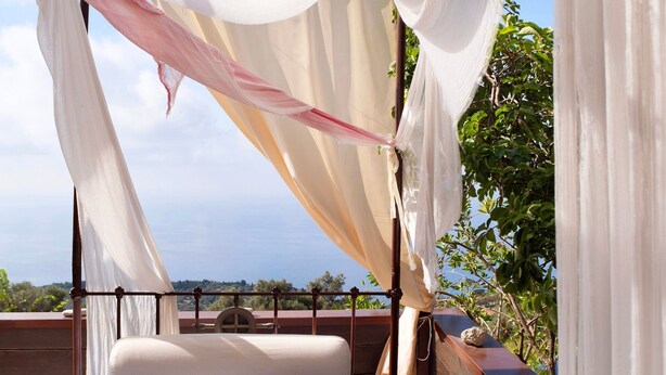 A bed with a canopy, a view of the sea, and a balcony with plants. - Apartment 'Villa Rojo Tajo Villas' with Sea View, Wi-Fi and Air Conditioning (Lefkada)