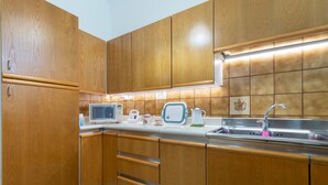 A compact kitchen with wooden cabinets, a microwave, a toaster, and a sink. - Apartment "Chicca Casa Vacanze" with Private Terrace & Wi-Fi (Bari)