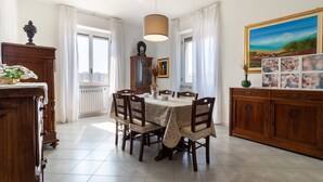 A dining room with a round table, chairs, a chandelier, a cabinet, and a painting. - Apartment "Chicca Casa Vacanze" with Private Terrace & Wi-Fi (Bari)