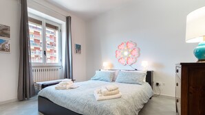 A bedroom with a bed, a window with curtains, a radiator, a wall decoration, and a lamp. - Apartment "Chicca Casa Vacanze" with Private Terrace & Wi-Fi (Bari)