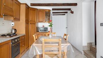 A kitchen with wooden cabinets, a microwave, a stove, and a dining table with chairs.