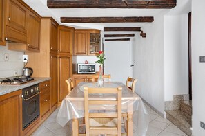 A kitchen with wooden cabinets, a microwave, a stove, and a dining table with chairs.