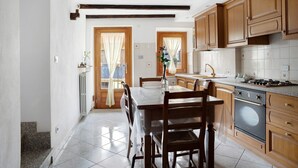 A kitchen with wooden cabinets, a dining table, chairs, and a stove.