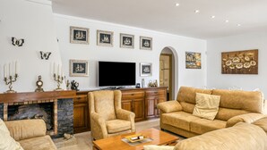 Una sala de estar con chimenea, televisor, sofá y mesa de centro.