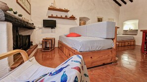 Una habitación acogedora con una cama, una mesita, un televisor y una chimenea.