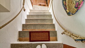 Una escalera con un felpudo rojo al final, una cuerda a los lados y suelo de baldosas.