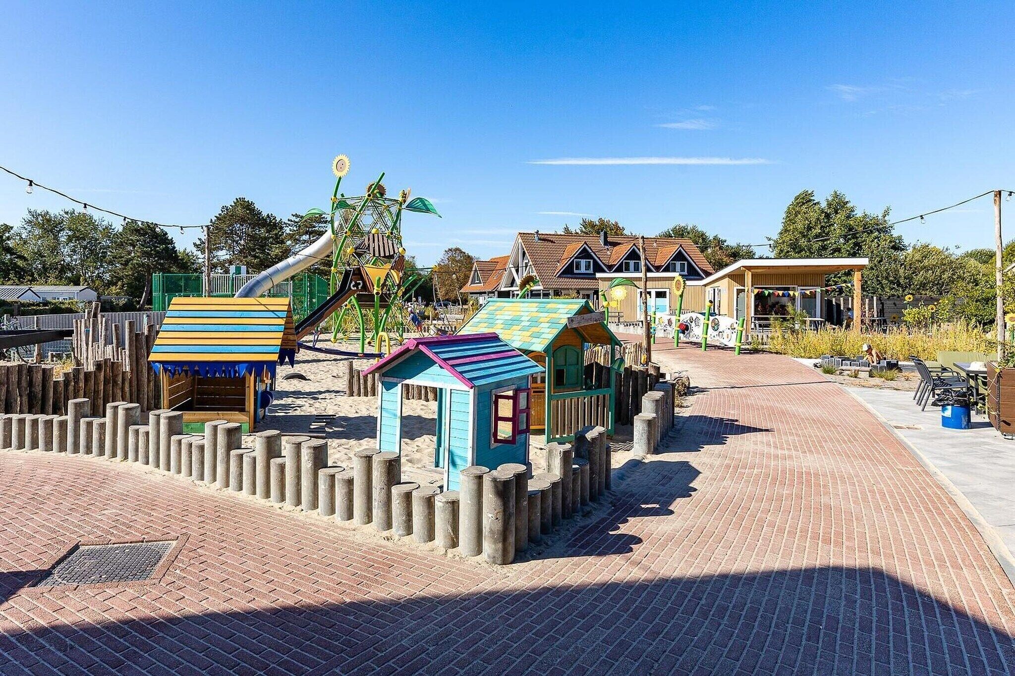 A playground with various play structures, a brick pathway, and buildings in the background.