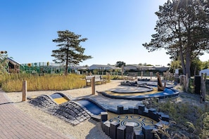 A playground with a circular play area, benches, and a fenced garden.