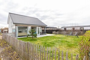 A single-story house with a tiled roof, a fenced backyard, and a small patio area. - Holiday Home in Renesse near the Beach (Renesse)