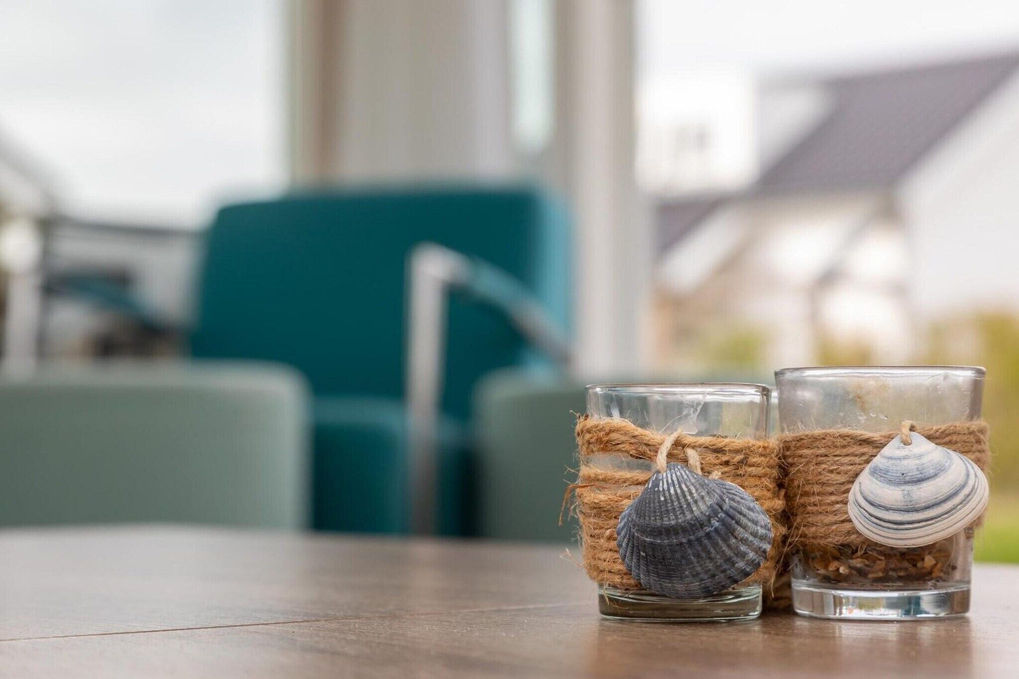 Two glass vases with seashells and twine on a wooden table.