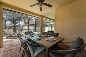 A dining area with a wooden table set for four, surrounded by cushioned chairs.