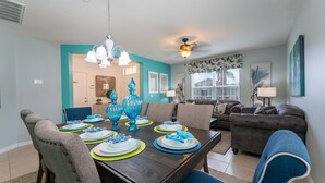 A dining area with a dark wooden table set for four, surrounded by chairs. - Coastal Decor-Hen's Nest- Privacy-Pool & Spa- Gated Community (Davenport)