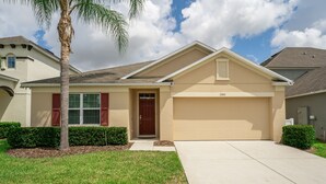 A single-story house with a beige exterior, a red door, and a garage. - Coastal Decor-Hen's Nest- Privacy-Pool & Spa- Gated Community (Davenport)