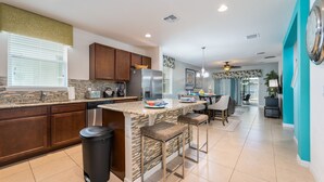 A modern kitchen with granite countertops, stainless steel appliances, and a central island with bar stools. - Coastal Decor-Hen's Nest- Privacy-Pool & Spa- Gated Community (Davenport)