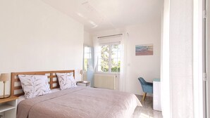 Une chambre à coucher avec un lit, des tables de chevet, une chaise, un radiateur et une fenêtre avec des rideaux.