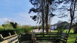 Une terrasse en bois avec une clôture rustique, un banc et un balai appuyé contre la clôture.