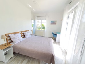 A bedroom with a bed, nightstands, a desk, and a chair.
