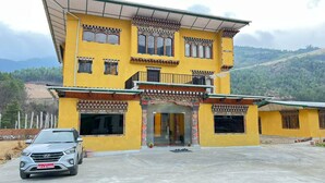 Un edificio de dos pisos con fachada amarilla, numerosas ventanas y un balcón.