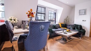 Un salon moderne avec un coin repas, comprenant un fauteuil recouvert de tissu bleu, un canapé et une table basse.